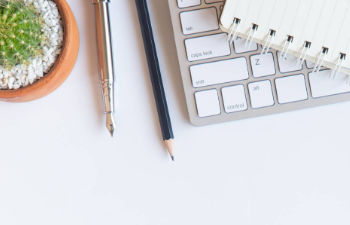 an office desk with a computer keyboard and stationeries