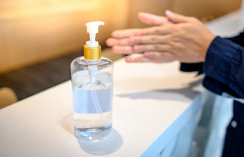 a person using disinfectant spray to clean hands