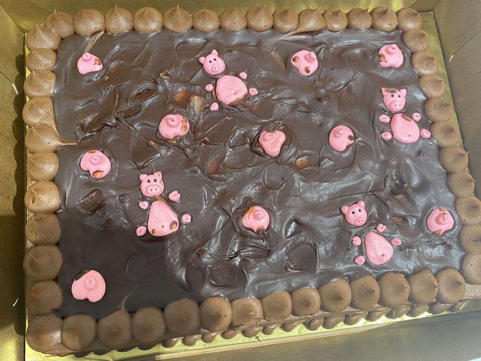 Cake decorated with sugar pigs bathing in chocolate mud